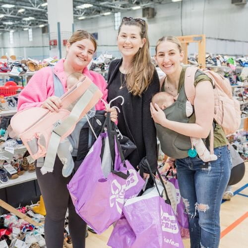 A mom, abuela and granddaughter attend a JBF sale in Dallas. Abuela is holding a babyseat.